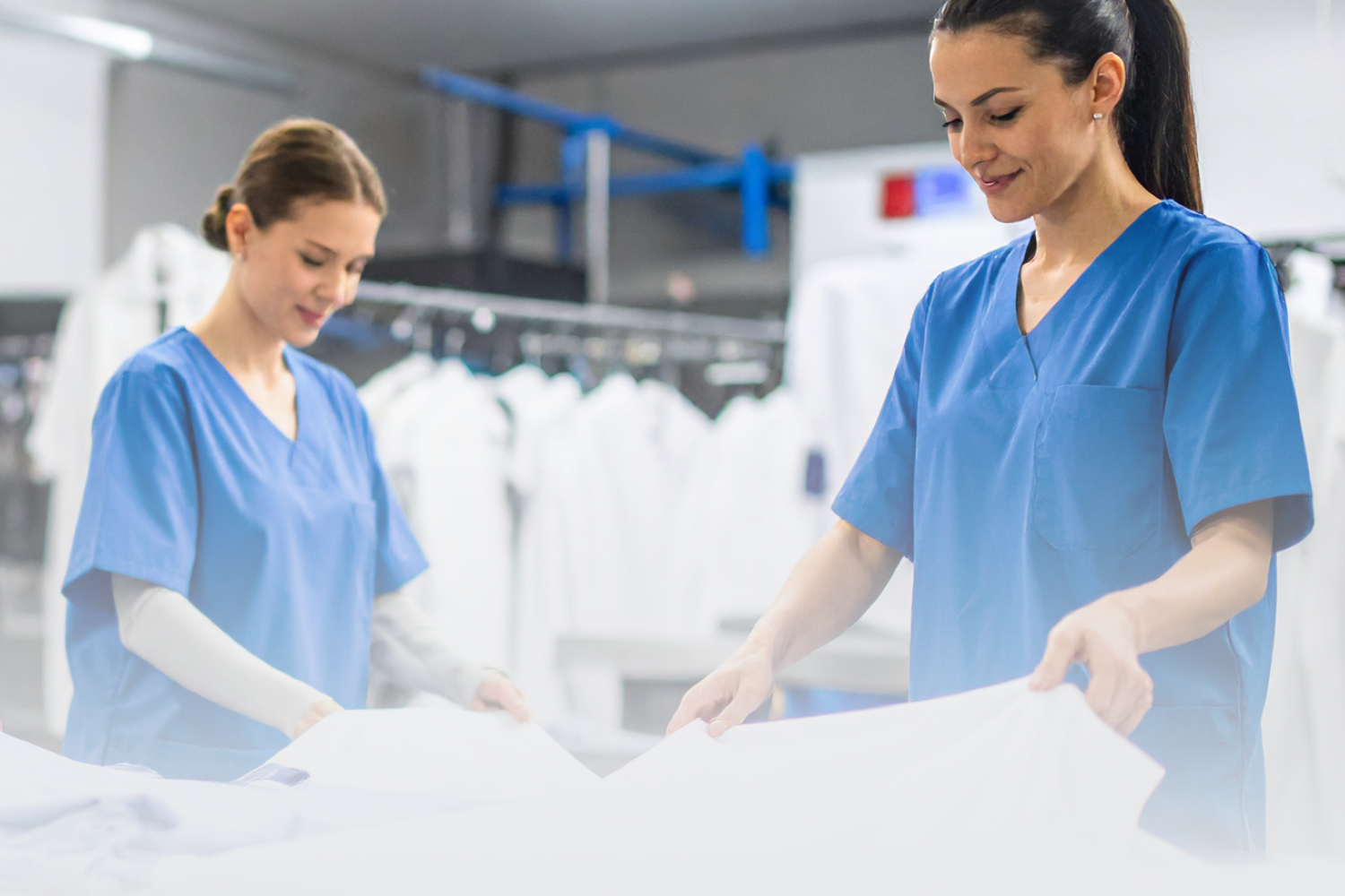 Deux femmes examinant une blouse de médecin dans une blanchisserie